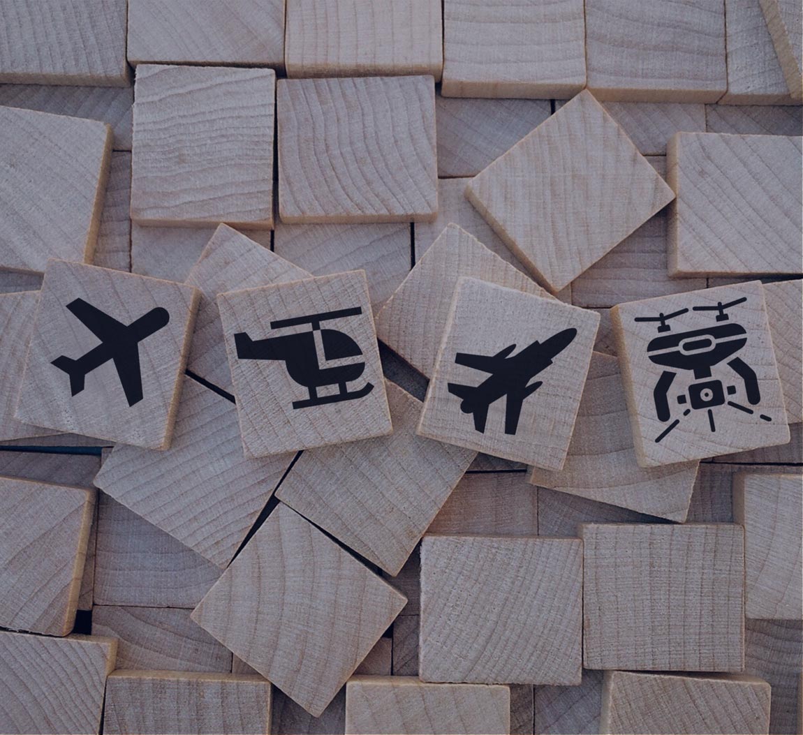 wooden block with a plane, a helicopter, a fighter plane and a drone drawn on it