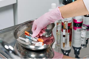 Hands on laboratory test tubes, syringes and basket