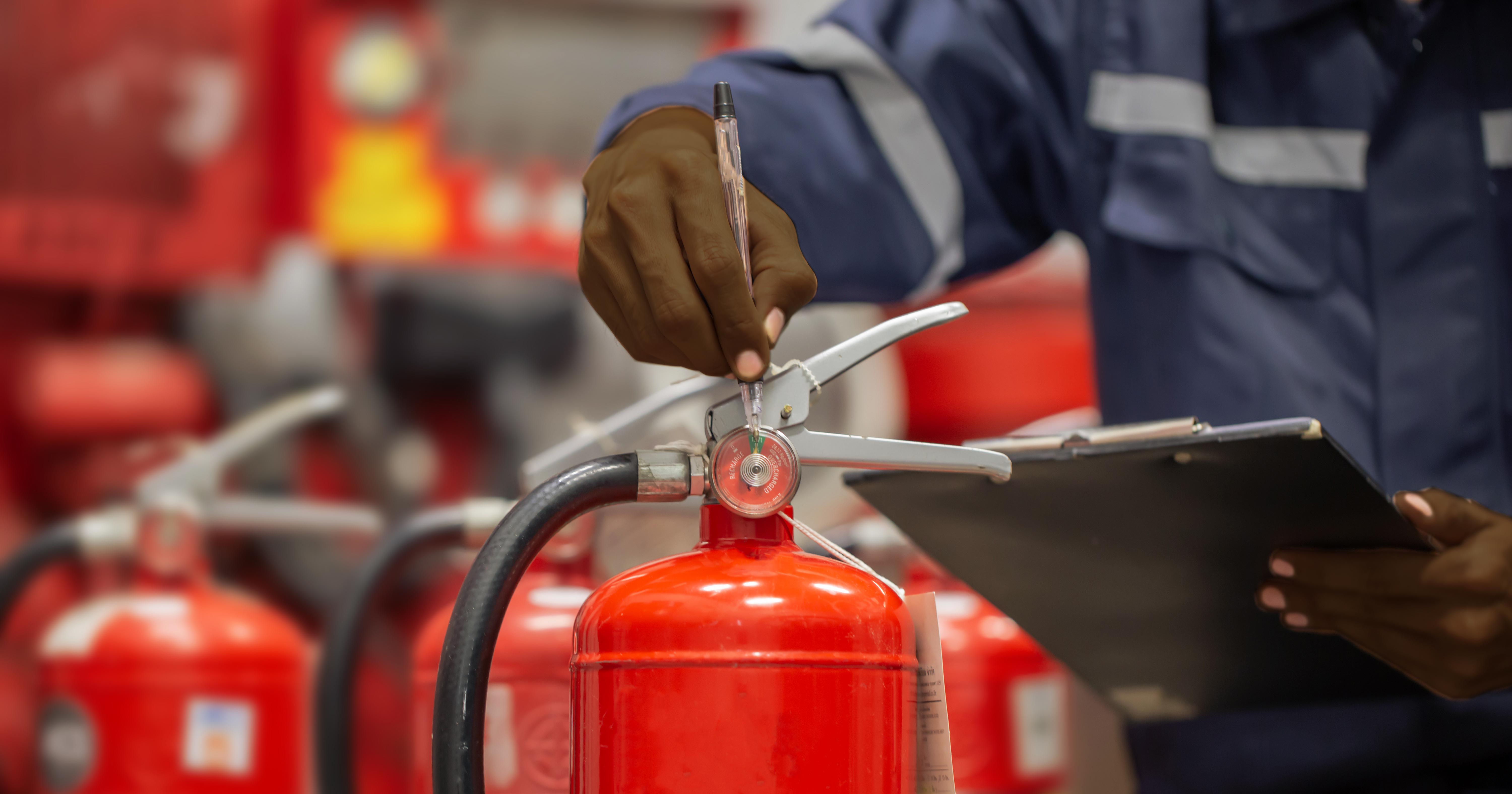 Apave employee inspects a fire extinguisher