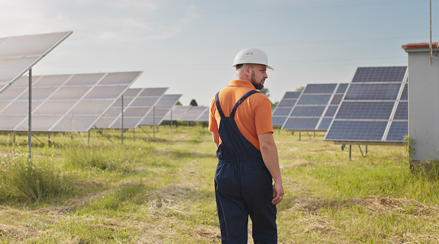 a man in work clothes in a field with solar panels