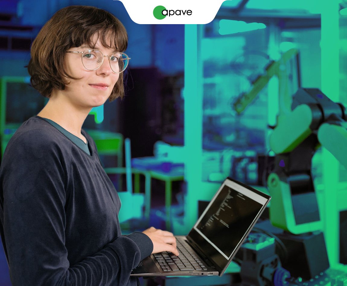 Une femme tient un ordinateur dans ses mains devant une ligne de production