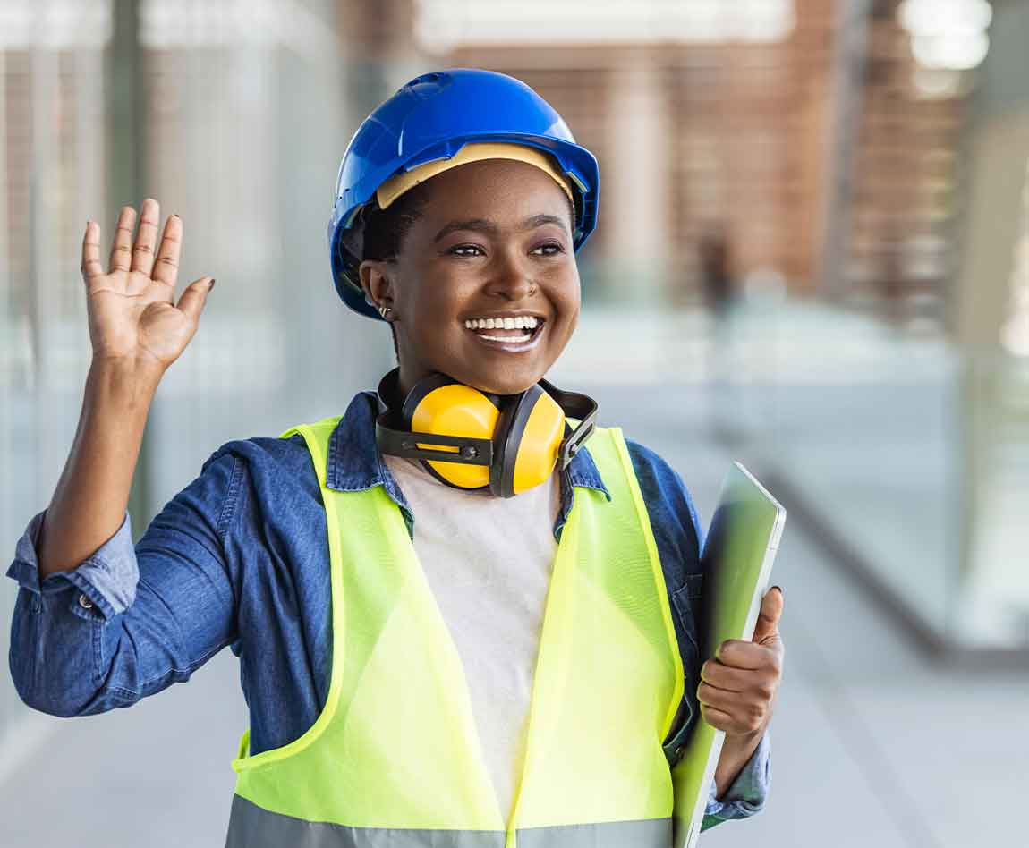 Portrait d'une jeune femme ingénieur avec un casque bleuet des plans dans les mains sur un chantier de construction.