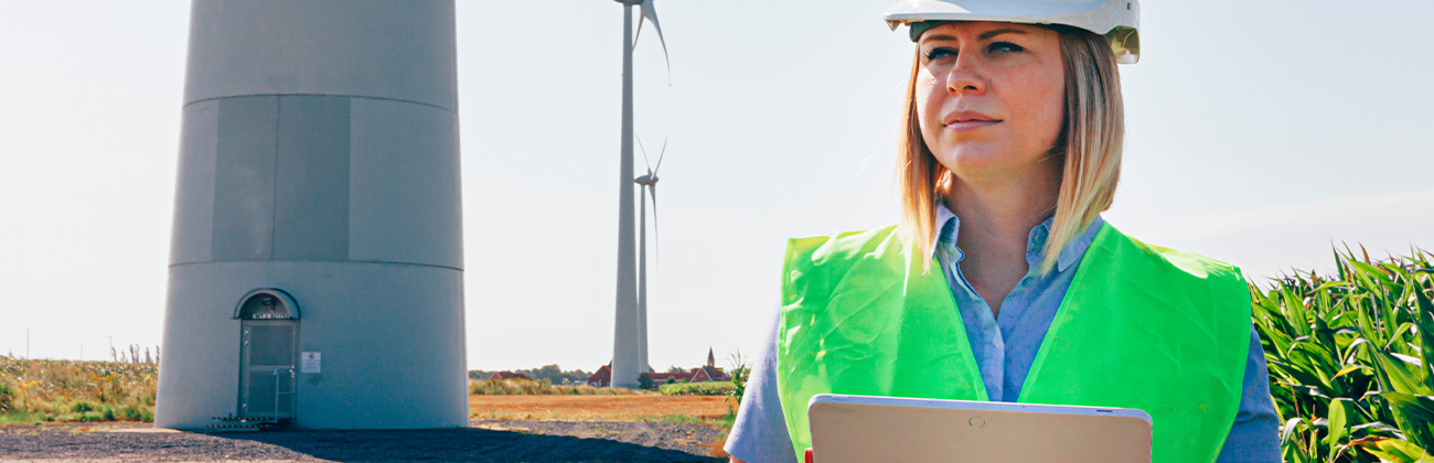 femme ingénieur éolien vérifiant une tablette dans un champ de turbines.
