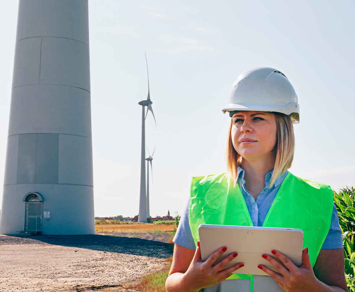 femme ingénieur éolien vérifiant une tablette dans un champ de turbines.