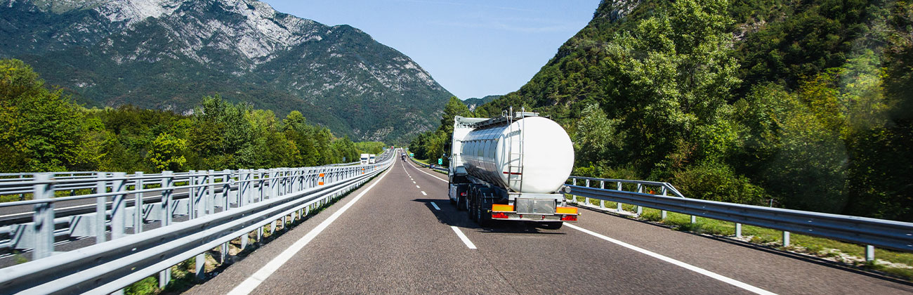 Un camion citerne roule sur l'autoroute avec une vue des Alpes en arrière plan.
