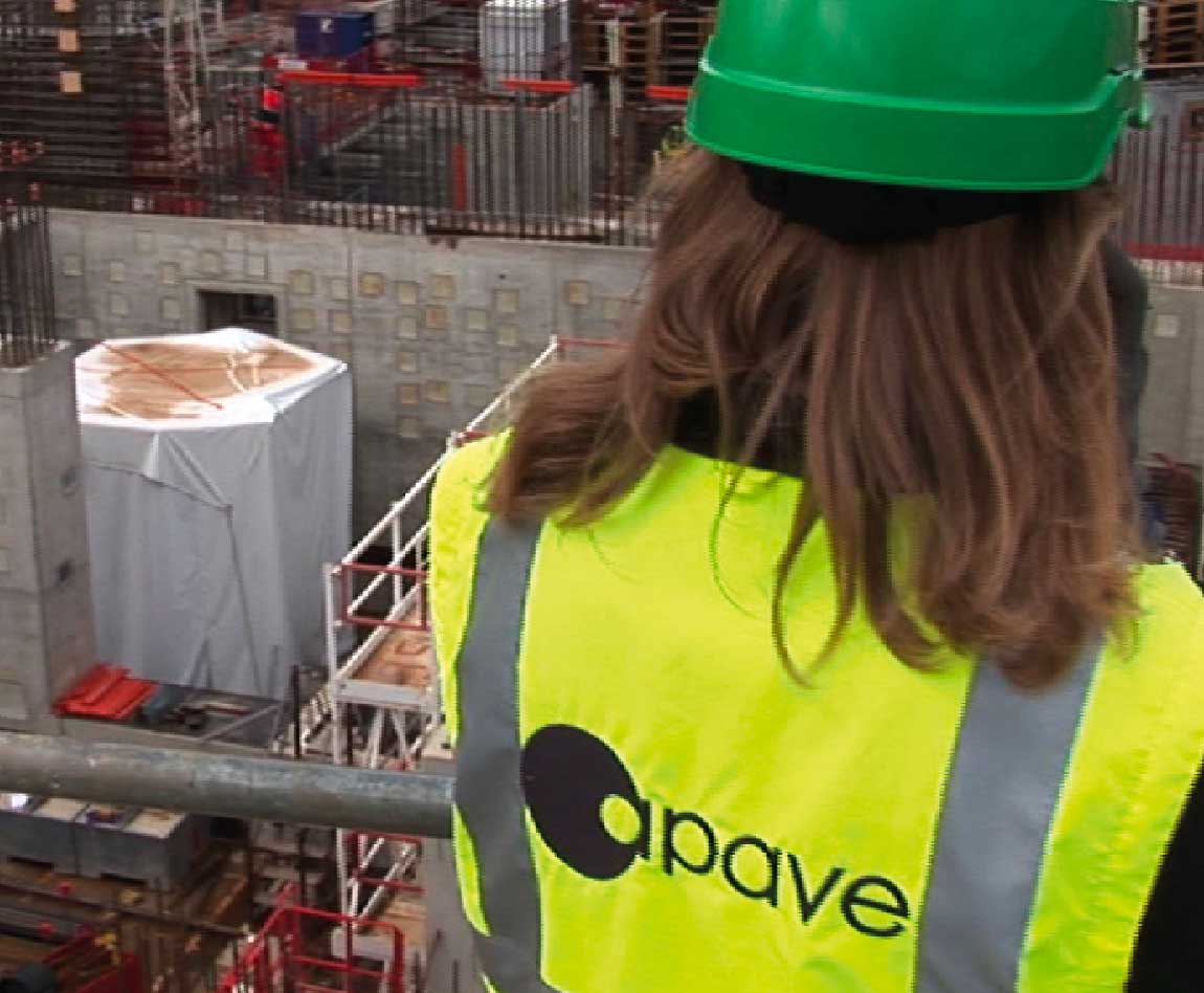 A woman wearing an Apave safety vest and helmet on a construction site