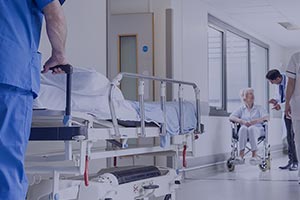 Dans un couloir d'hôpital, un homme pousse un lit médical