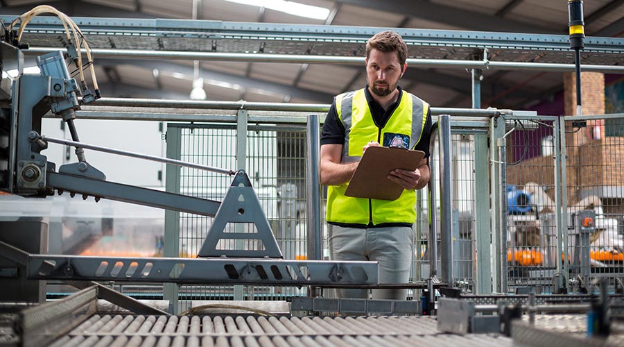 A man in a yellow waistcoat controlling a production line