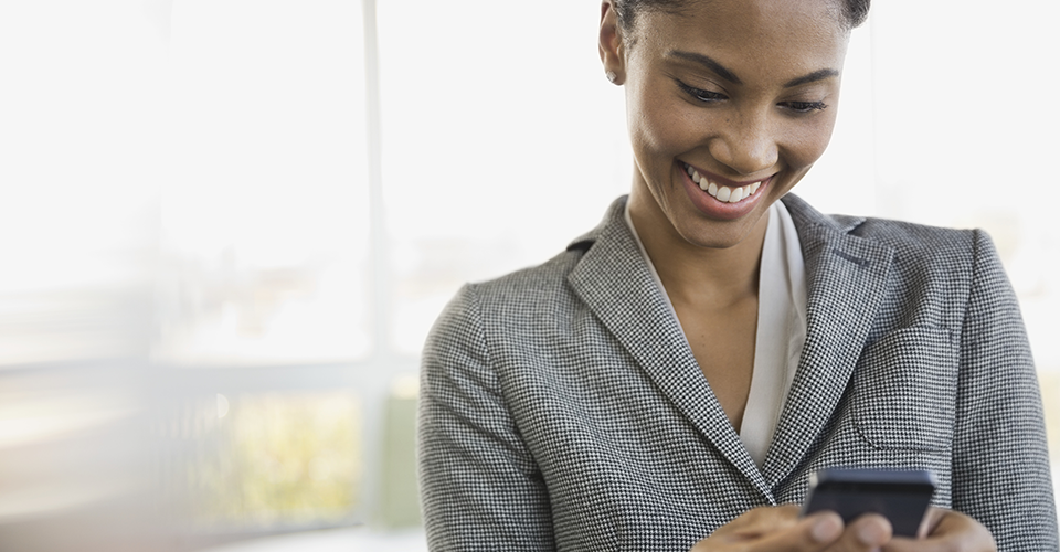 a young woman is smiling while looking at her phone